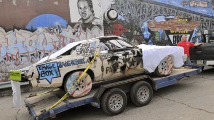 Jason Sauer, the founder of Most Wanted Gallery, stands with his demolition derby art car Thursday in Garfield.
