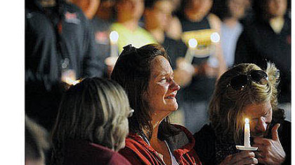 Denise McNerney holds a candle and weeps as she sits in front of members of the football team during Thursday's vigil following the killing of her son, Tim.