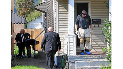 Westmoreland County detectives investigate at a house on Third Avenue in Arnold on Friday. Police said a mother and her grown son were slain in the home.