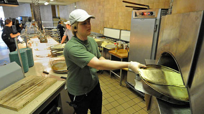 Devon O'Leary slides a calzone into the pizza oven at Shippensburg University's Reisner Dining Hall.