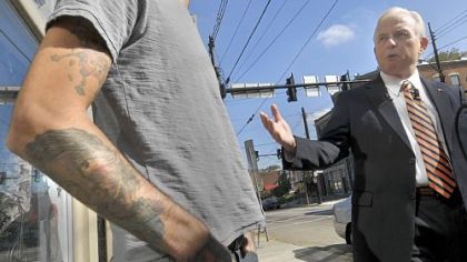 Auditor General Jack Wagner, right, stands in front of  Rogue Tattoo in Lawrenceville with shop owner Travis Courtemanche while answering reporters' questions.