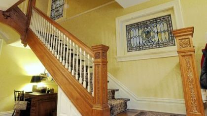 Ty Ely spent more than seven months stripping white paint from this oak staircase. The stained-glass windows are both original.