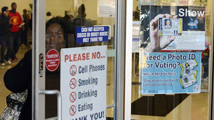 A woman walks past a voter identification poster today at the PennDOT drivers' license center in Penn Hills.