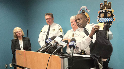 Pittsburgh Police Chief Nate Harper holds up the bullet-resistant vest worn by Officer Andrew Baker, to show the bullet hole in the center chest area.