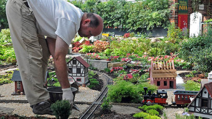 Kevin Ajughey spreads ballast along the train tracks in the Garden Railroad as the finishing touches are done for the fallshow at Phipps Conservatory.
