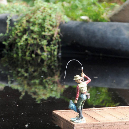 A fisherman casts a line into the pond near the model railroad in Phipps Conservatory.