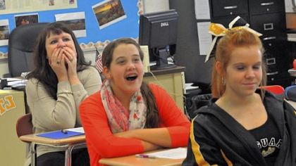 Sitting behind eighth-grade students Julia Horvitz and Mikayla Horick, both 13, in a social studies class, science teacher Christina Becker reacts to a student's attempt at reading the news like a "town crier."