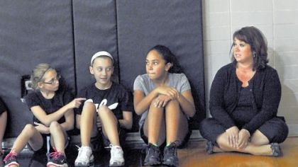 Melissa Gambino, right, a science teacher at Pleasant Hills Middle School, sits Wednesday with sixth-grade students in gym class == from left, Kaley Kuzma, Morgan Newton and Sierra Henning, all 11.