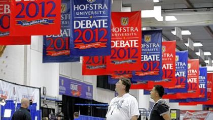 Billy Koske, left, and Jose Reyes look at signs hanging Monday in the media center before tonight's presidential debate at Hofstra University in Hempstead, N.Y.
