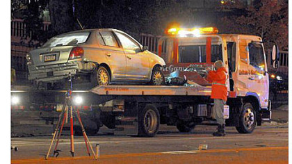 Mangled parts of a car are collected after the vehicle, which was being pursued by police, collided with a garbage truck at 34th Street and Liberty Avenue.