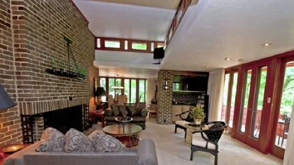 A wood-burning fireplace with a wrought-iron screen is found in the living room, which measures 21 by 18 feet and offers access to the 14- by 4-foot cantilevered balcony.
