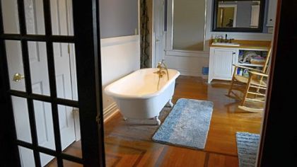 The master bathroom, a former bedroom, has a French door between the bedroom and bath, a double-bowl sink, and a clawfoot tub.