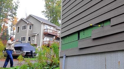 Greg Mortimer walks near one of the villas at Cedar Creek. The siding has been pulled off to check damages from the leaks. The villa is one of four that have several leaks.