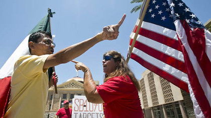 Andy Hernandez, left, carrying a Mexican flag, and Allison Culver, carrying an American flag, continue the discussion over Arizona's immigration law outside the State Capitol in Phoenix.