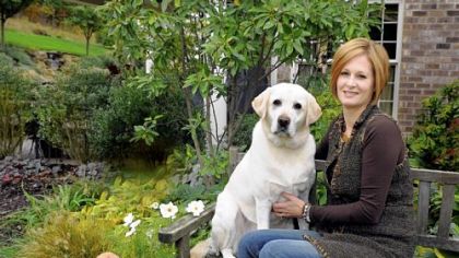 Rose Romboski and her yellow lab, Ashton, in her garden.