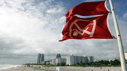 Red flags fly from a lifeguard station as Hurricane Sandy passes east of Miami Beach today. Sandy could blend with a winter storm and reach the East Coast as a super-storm next week.
