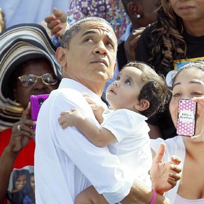 President Barack Obama carries a baby as he prepares to leave a campaign stop in Delray Beach, Fla., Tuesday, Oct. 23.