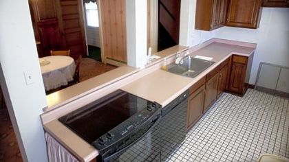 The cooking space is a galley with solid-surface counters, an electric cooktop/stove and a dishwasher.