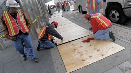 Metropolitan Transportation Authority workers cover subway ventilation grates with plywood Friday to help prevent flooding at South Ferry in New York.