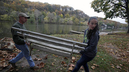 Jonathan Nice, left, and his daughter Emily, of Landsdale, Pa., move a bench to a shed as they help a friend pack up his private dock in preparation for severe weather.