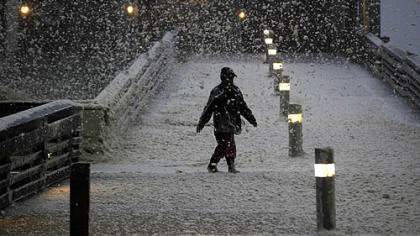 High winds blow sea foam into the air as a person walks across Jeanette's Pier in Nags Head, N.C. on Sunday.