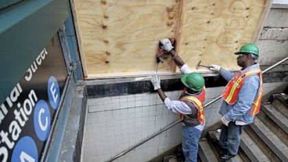 Metropolitan Transportation Authority workers cover an entrance Saturday to the Canal Street A, C and E subway station in New York's Manhattan borough with plywood to help prevent flooding. As Hurricane Sandy approaches the New York region, residents of some flood-prone areas have been told to evacuate and officials are preparing for a possible transit system shutdown.
