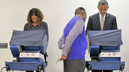 An election worker helps President Barack Obama as he completes early voting on Thursday at the Martin Luther King Community Center in Chicago.