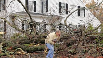 John Constantine makes his way out of his house after winds from Hurricane Sandy caused a tree to topple over and fall onto it Monday in Andover, Mass.