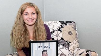 Logan Robinson, 13, holds a photo of her father, R.J., who died from pancreatic cancer. She will pour purple dye into the fountain at Levin Furniture in Monroeville at 12:30 p.m. today to raise awareness of the disease.
