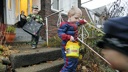 Supertwins Liam Harencame, left, as the Hulk, and Garret Harencame, center, as Spiderman, trick-or-treat at the home of Cortney Meade, background, in Lawrence Park, Pa., on Wednesday. Ms. Meade said despite the rain, she enjoyed handing out candy.