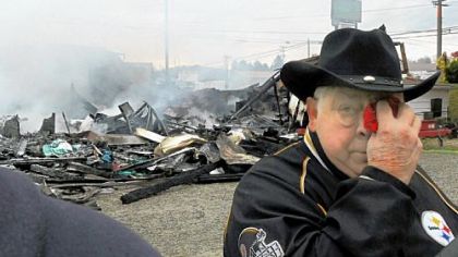 Valley Billiards owner Burley Hartin dabs his eyes while his business near New Alexandria smolders in the background on Friday.
