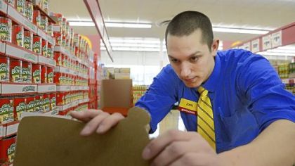 Manager Josh Leroux puts pricing stickers on products Thursday at the new Good Cents grocery store on McKnight Road.  The store opens Sunday.