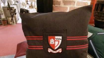 Private school blazer crests on pillows from Fanshawe Blaine Antiques & Interiors.
