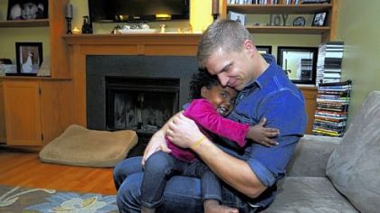 Rob Szenyeri hugs his daughter, Mae, in the family room of their Cranberry home.