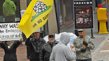 People with contrasting opinions about President Barrack Obama and the Republican challenger Mitt Romney stand at the back of the crowd before former U.S. President Bill Clinton arrived in Market Square.