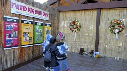 Joann Vaughn of Mt. Lebanon and her boys, Jack, 6, and Walker, 4, visit the entrance to the overlook of the African painted dog exhibit at the Pittsburgh Zoo & PPG Aquarium. The zoo has placed wreaths at the entrance, and visitors have left toys and flowers. The exhibit is now closed after the death of a 2-year-old boy Sunday.