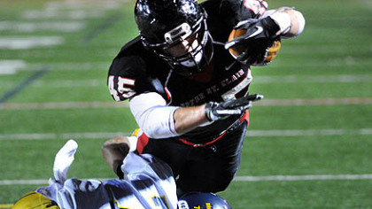 Upper St. Clair running back Mac Pope dives over Central Catholic's Todd Coles for a 5-yard touchdown in the first half Friday at Baldwin High School.