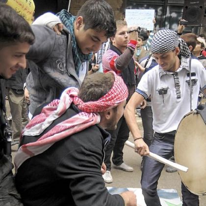 Syrian youth dance on a poster depicting President Bashar Assad at a demonstration Friday against his regime in the Bustan al-Qasr district of Aleppo, Syria.