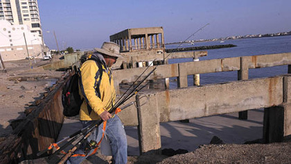 Ray Guangon of Cherry Hill, N.J., crosses over the remains of the boardwalk north of the casino district in Atlantic City to go fishing today. The boardwalk in front of the casinos remained intact, only an older section of the boardwalk north of the Revel casino was demolished.