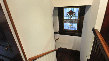 Stained glass window on staircase landing between first and second floor.