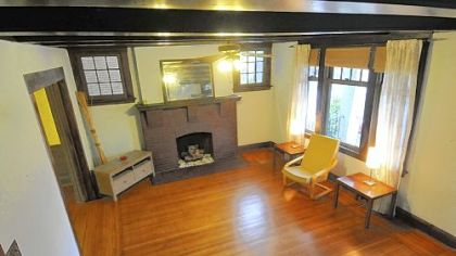 The living room features a brick fireplace and  horizontal wood beams across the ceiling.