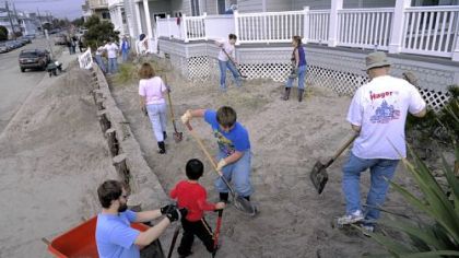 Relatives of the Hoover family help shovel feet of sand Saturday from around the exterior of the family beach home in Ocean City, N.J. From left, Andrew Malloy of Carlisle, Pa., Alex Elicker, 3, with his brother Ethan Elicker, 10, both of Elizabethtown, Pa., and Ken Hoover of Lancaster, Pa.
