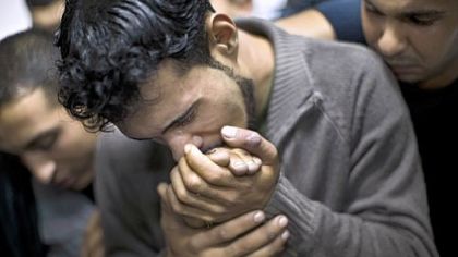 A Palestinian man kisses the hand of a dead relative Sunday in the morgue of Shifa Hospital in Gaza City.