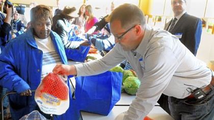 Getting in the holiday spirit, Penguins coach Dan Bylsma passes out a turkey to Bernivine Nixon, 78, at Oak Hill Food Pantry in the Hill District on Friday.