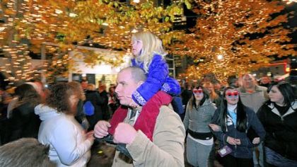 Haily Pollack, 3, of Port Vue sits atop her father Brad's shoulders as he makes his way through the crowd at PPG Place Plaza during Light Up Night festivities on Friday.