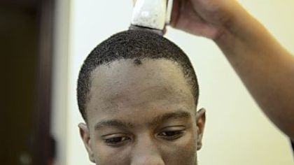 Quarterback Armani Ford, 17, gets his hair cut by Stuart Price, owner of Hot Towels and Sharp Razors, before Clairton's last regular-season home game. "It's a lot of pressure [to be the quarterback]. You need the team on your side, plus the city is watching over you," Ford said.