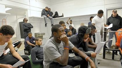 Titus Howard, center, a junior wide receiver and cornerback who has made a verbal commitment  to play football at the University of Pittsburgh, and his Bears teammates listen to defensive coach Wayne Wade during a recent strategy session in  the  team's weight room.