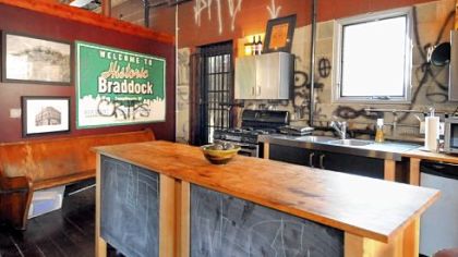 The kitchen area in the second floor open room in the Fettermans' home has the last pew from the former First Presbyterian Church, old signs and photos from the town, and commissioned graffiti. Chalkboards on the center island allow children to draw with chalk.