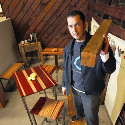 Sal Tamayo, 35, owner of Against the Grain, shoulders a timber of "rescued" wood once used as dunnage by a steel shipping company. He salvages the castoff exotic hardwood from the Port of Los Angeles and makes tables, chairs and benches.