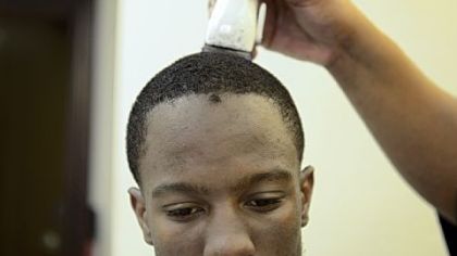 Quarterback Armani Ford, 17, gets his hair cut by Stuart Price, owner of Hot Towels and Sharp Razors, before Clairton's last regular-season home game. "It's a lot of pressure [to be the quarterback]. You need the team on your side, plus the city is watching over you," Ford said.